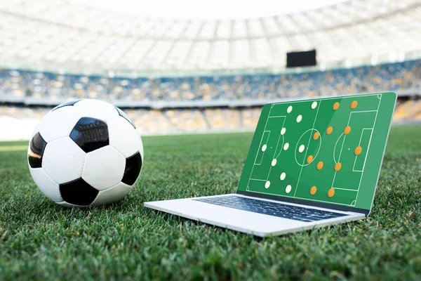 A Soccer Ball and  a Laptop on green grass